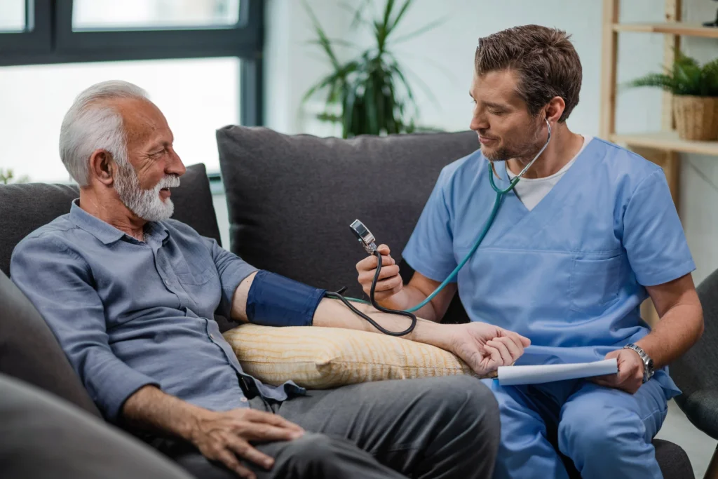 heureux medecin generaliste mesurant la pression arterielle d un homme mur lors d une visite a domicile