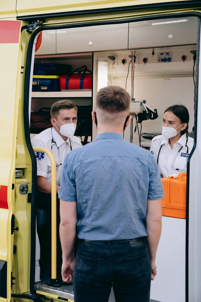 Soins infirmiers à domicile au Maroc Ambulance crew assists a man outside an emergency vehicle, wearing masks.