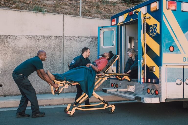 Infirmier à domicile : First responders assist an injured man onto a stretcher and into an ambulance during a daytime emergency call.